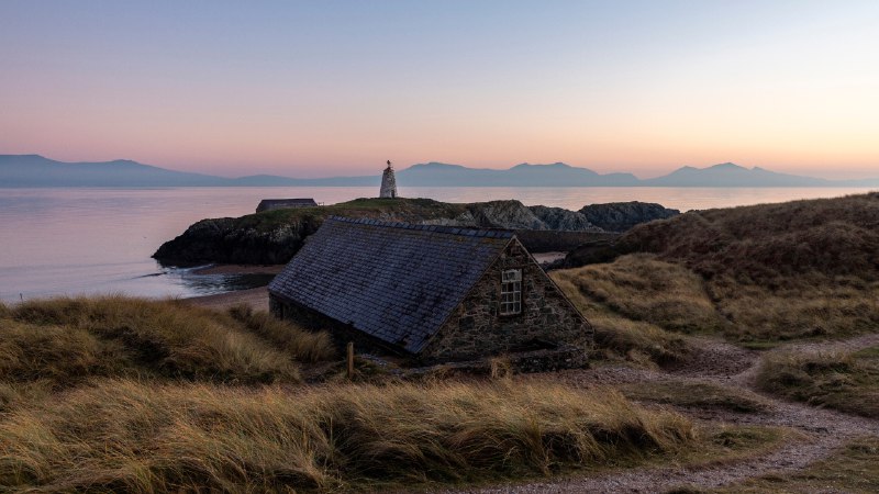 'Welsh' you a Happy Hen Galan!Cottage with Tŵr Mawr Lighthouse in the background, Ynys Llanddwyn, Wales (© Westend61 on Offset/Shutterstock)