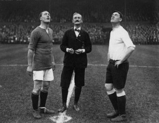 The captains of Chelsea and Tottenham, along with an elegant referee, watch the toss of a coin before the match. 1913.Time Machine | Historical Photo