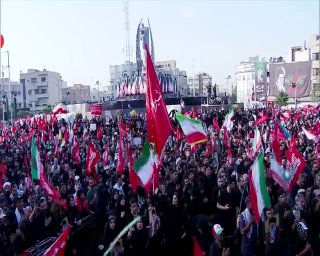 🎦 הנוכחות של אנשים היא תמיד על הבמה בכיכר אינג'לב בטהראן עם סמל אגרופו הקמוץ של המנהיג ההרוג