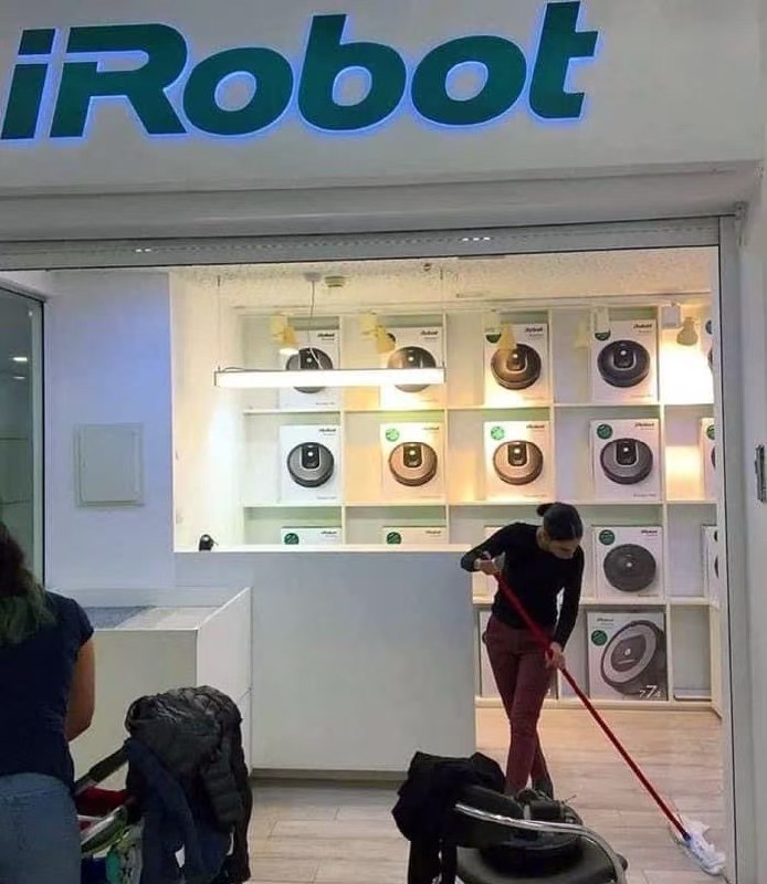 扫地机器人店里，店员拿着扫帚扫地