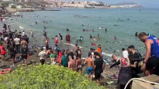 מהגרים מרוקאים נכנסים דרך הים לאזור המבוצר הספרדי של Ceuta, שם אחד מהם נושא אופניים תוך כדי שחייה במים.