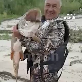 Утро. Якутия. Светает. Мужчина лет 60 в камуфляжной одежде держит в руках щуку размером 100-150 см и весом 16кг. Рыбак очень доволен.❗ Не грузятся фото и видео? Читайте нас в MAX