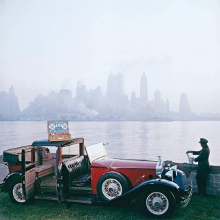 A chauffeur takes a picnic set out of the trunk of a Rolls-Royce against the backdrop of New York City scenery, 1930s.Time Machine | Historical Photo