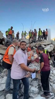 דובר ההגנה האזרחית של עזה, מחמוד באסל, מחזיק בילד שנהרג, שקם היום עם שחר לאחר שבניין קרס על תושביו בעיר עזה, ומעביר מסר לעולם הדומם.