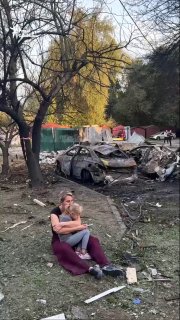 Heartbreaking. A mother holding a child sits beside a large crater in the courtyard of an apartment building in Boryspil today, destroyed by Russian strikes.