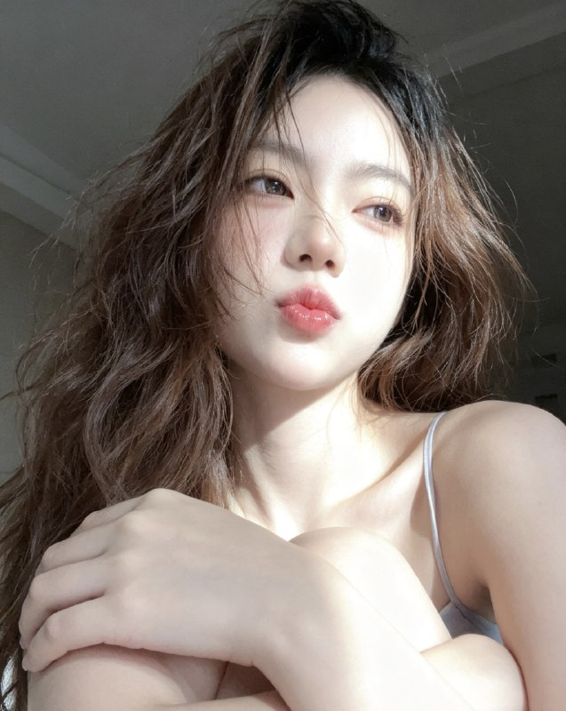 分享一个魔法提示词，坐等美女们返图以照片中的人物为原型，生成9张不同姿势的写真 不要项链，不要背包，低角度仰拍，画面微倾斜，营造随性抓拍感，直接复制就能用，轻松拍出纯欲氛围感写真，背景为色调偏中性且模糊的昏暗房间，年轻的韩系美女，冷白色的皮肤，一头深棕色的长波浪卷发显得有些凌乱，发丝随意地垂落在脸庞和眼睛上，身着一件细肩带的浅色上衣，脸上带着一种微妙的纯欲表情，半睁着慵懒的双眼微微向右看，双唇丰满且带着光泽，呈现出粉中透红的颜色，嘴唇微微撅起，流露出柔和的忧郁又诱人的气质，双手托着头，手指轻按脸颊、双手托腮，手指轻按脸颊，手肘自然支撑，无浓妆，仅唇部有光泽感，突出原生妆容质感