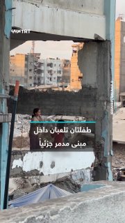 Two Palestinian girls play inside a building that was partially destroyed by the occupation bombing during the war of extermination in the Gaza Strip, in Mashhad, where the innocence of childhood is mixed with the effects of destruction.