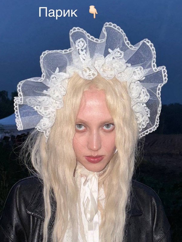 Выбор цвета и работа с формой: 2 парик — блонд для нового образа RARAДля следующего образа мы хотели отойти от «натуральной» эстетики предыдущих кадров и перейти к образу, вдохновлённому историей — с выраженной формой, утончённостью, женственностью и цветом, близким к канонам моды того времени.Задача — считать героиню из прошлого, но показать её современно: за счёт лёгкой небрежности, простоты исполнения.Этапы работы с парикомПодготовка текстуры:Дала волосам высохнуть естественно — это позволило получить натуральную волну без стайлеров.База:Выполнила начёс по всей голове — от корней до концов — оставив нетронутыми лишь краевую линию (примерно 3 см вглубь) и нижнюю зону затылка.Это сохраняет аккуратность по периметру и создаёт «воздушный фундамент» внутри.Формирование конструкции:Затылочную часть вычесала наверх в плоский на затылке, объёмный к макушке валик — основа будущей формы.Волосы от лица также уложила объёмно и закрепила к зоне предыдущего валика (на макушке), тем самым задала движение назад.Детали:Виски подтянула к затылку и зафиксировала — так задаётся правильное направление у лица, нужные корректирующие линии.На затылке можно:• заплести косичку,• завить локоны и оставить,• собрать полностью, ничего не опуская вниз.Аккуратно разложила оставшиеся у лица волосы, формируя мягкие, выразительные пряди.Декор:Добавила украшения — акцент, который неотъемлемая часть прически того времениВыбор цвета и работа с формой: 2 парик — блонд для нового образа RARAДля следующего образа мы хотели отойти от «натуральной» эстетики предыдущих кадров и перейти к образу, вдохновлённому историей — с выраженной формой, утончённостью, женственностью и цветом, близким к канонам моды того времени.Задача — считать героиню из прошлого, но показать её современно: за счёт лёгкой небрежности, простоты исполнения.Этапы работы с парикомПодготовка текстуры:Дала волосам высохнуть естественно — это позволило получить натуральную волну без стайлеров.База:Выполнила начёс по всей голове — от корней до концов — оставив нетронутыми лишь краевую линию (примерно 3 см вглубь) и нижнюю зону затылка.Это сохраняет аккуратность по периметру и создаёт «воздушный фундамент» внутри.Формирование конструкции:Затылочную часть вычесала наверх в плоский на затылке, объёмный к макушке валик — основа будущей формы.Волосы от лица также уложила объёмно и закрепила к зоне предыдущего валика (на макушке), тем самым задала движение назад.Детали:Виски подтянула к затылку и зафиксировала — так задаётся правильное направление у лица, нужные корректирующие линии.На затылке можно:• заплести косичку,• завить локоны и оставить,• собрать полностью, ничего не опуская вниз.Аккуратно разложила оставшиеся у лица волосы, формируя мягкие, выразительные пряди.Декор:Добавила украшения — акцент, который неотъемлемая часть прически того времени