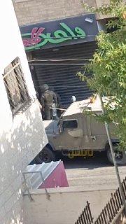 כוחות הכיבוש הישראליים מנסים להסיר את דלתות חנות ליד בית הספר דאפר אל-מסרי.