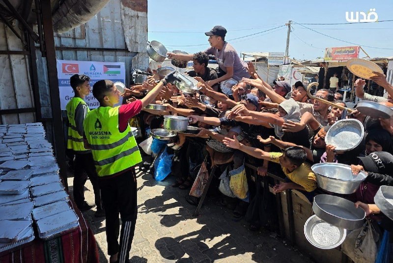 Displaced Palestinians gather at a charity kitchen in Khan Younis, southern Gaza, in an effort to obtain food for their … - news image