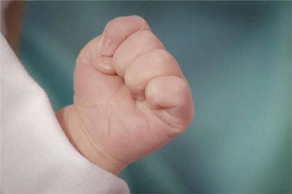 Why does a human’s fist remain clenched when they enter the world and open when they leave it?