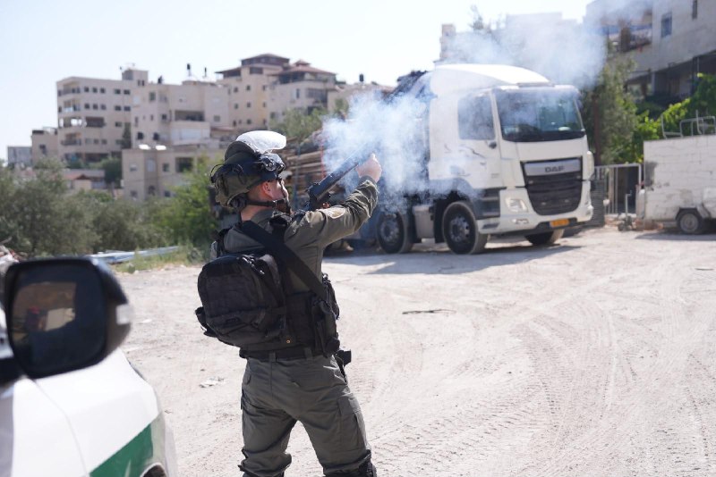 A Border Police officer fires a crowd-control gas canister on an East Jerusalem street.